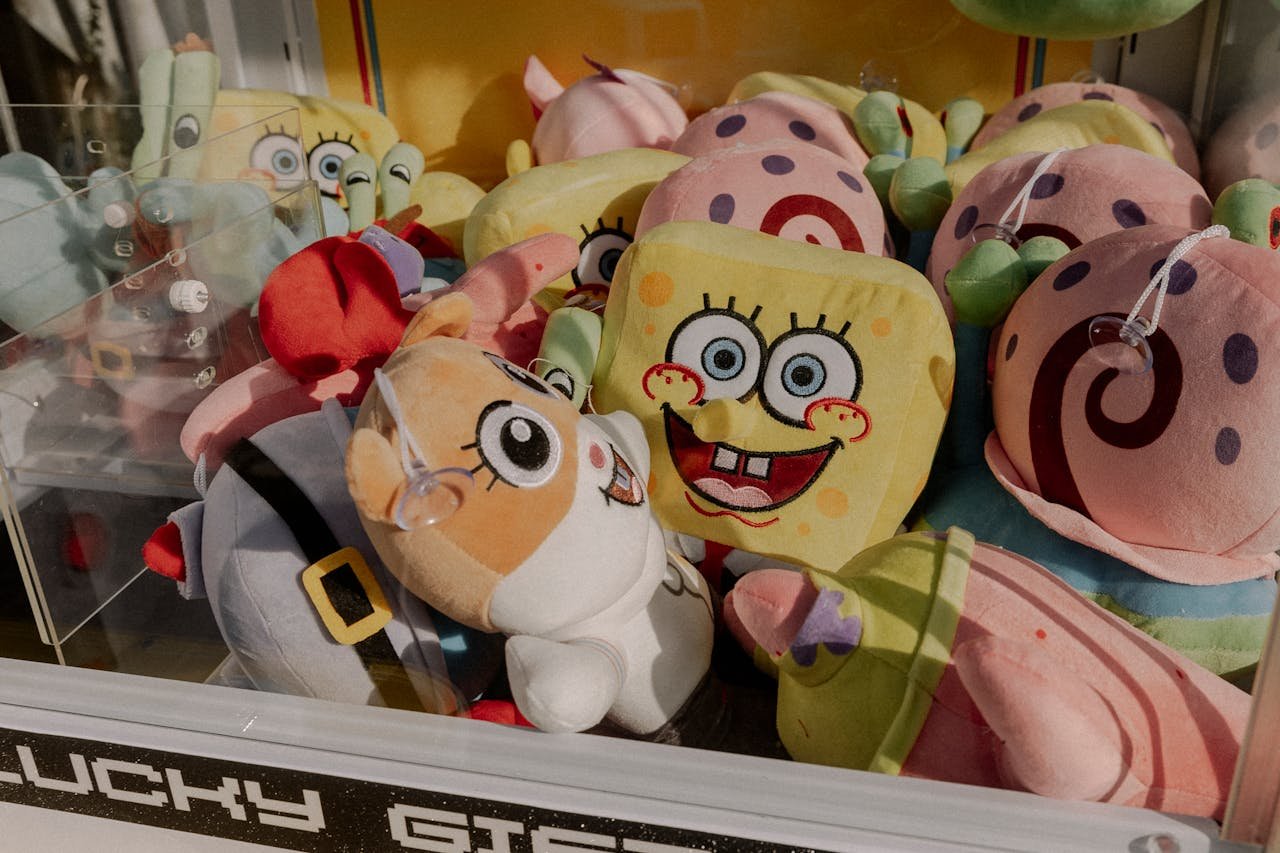 about-04 A vibrant claw machine filled with various plush toys at an arcade, offering fun entertainment.